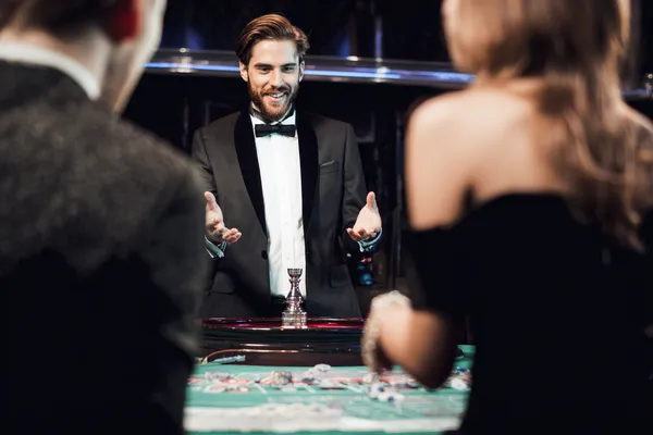 A professional dealer in a tuxedo greeting players at the roulette table, symbolizing the authentic live casino feel at SPINARA.