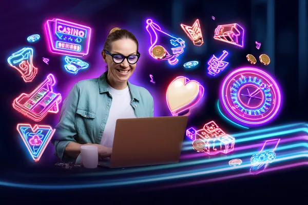 A woman smiling while playing online games on her laptop, surrounded by neon casino elements, showcasing SPINARA’s diverse game collection.